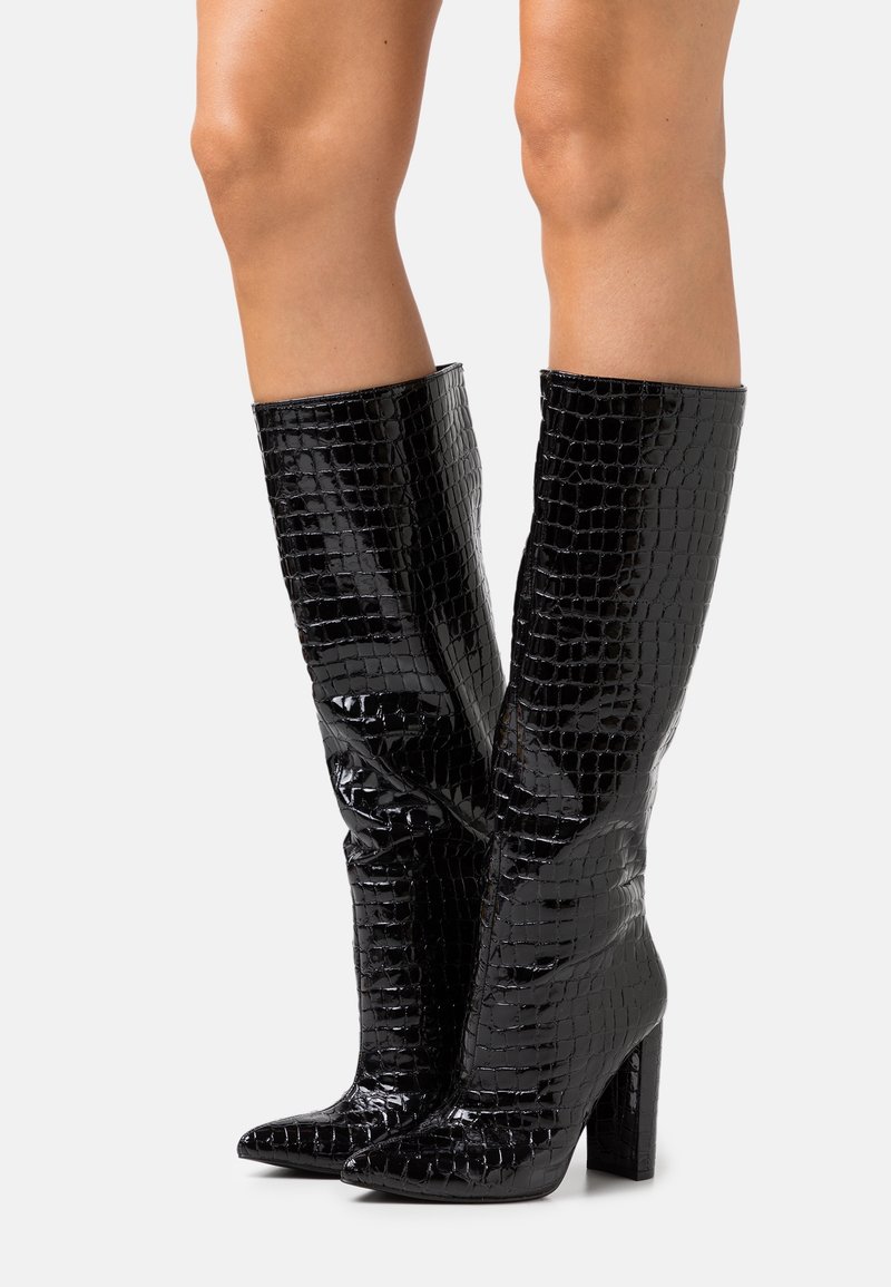 Bottes noires mi-mollet à la texture crocodile brillante, bout pointu et talon épais. Fini lisse sans quincaillerie ni accents visibles.