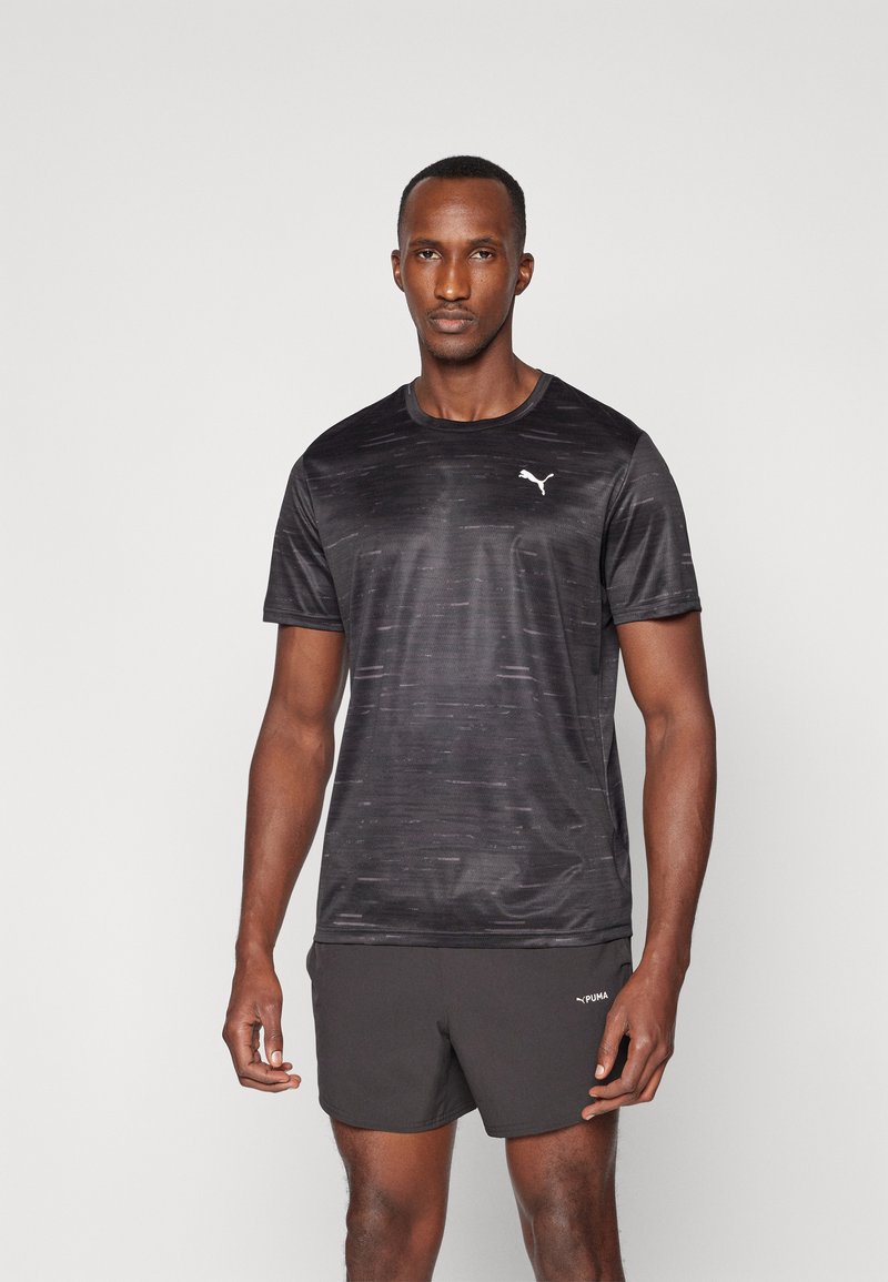 Zwart sport T-shirt met textuurpatroon en ronde halslijn. Witte logo op de linker borst. Gepaard met zwarte shorts, met een subtiele merketiket.