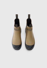 Tan waterdichte enkellaarzen met zwarte rubberen neuskappen, Barbour-logo op de voorkant en hiel, strak ontwerp en zonder veters.