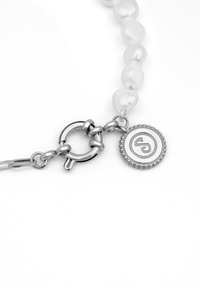 Pulsera de perlas con un cierre de plata y un charm circular que presenta un diseño en espiral, mostrando un acabado suave y brillante.