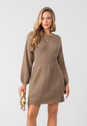 Abito in maglia marrone chiaro con un motivo testurizzato, maniche lunghe a sbuffo, vita aderente e orlo svasato. Borsa a tracolla con catena in tonalità oro.