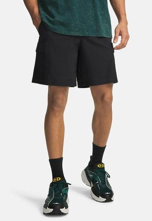 Zwarte cargoshorts met een losse pasvorm, zijzakken, een gladde textuur, gecombineerd met groene sportschoenen en zwarte kousen.