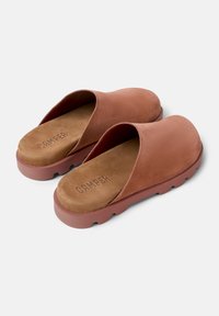 Bruine suède instap schoenen met een gladde bovenkant, een gewatteerde binnenzool en een gestructureerde rubberen zool met afgeronde randen en een logo opdruk.
