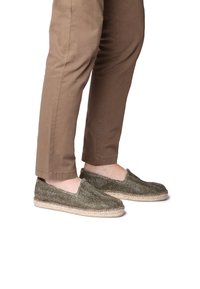 Espadrilky v tmavozelenej tkanine s okr�úhlou špičkou, jute medzipodrážkou a elastickými stranami, v kombinácii s khaki bavlnenými nohavicami.