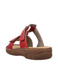 Sandale en cuir rouge avec des sangles Velcro, dos ouvert, semelle intérieure rembourrée et semelle texturée marron. Présente des coutures le long du bord.