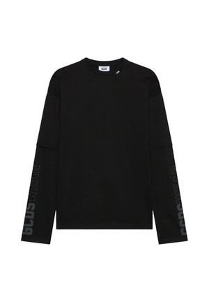 Maglietta nera a maniche lunghe a strati con testo "GCDS WEAR" sulle maniche e piccole etichette "GCDS" vicino allo scollo.