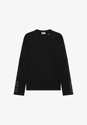 Maglietta nera a maniche lunghe a strati con testo "GCDS WEAR" sulle maniche e piccole etichette "GCDS" vicino allo scollo.