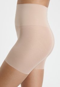 Shorts beige modellanti con una vita alta, caratterizzati da un motivo a rombi testurizzato, una finitura liscia e aperture per le gambe senza cuciture.