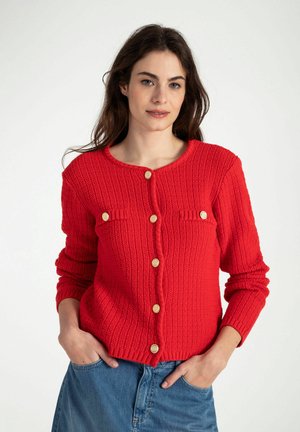 Rode gebreide cardigan met een textuur patroon, gouden knopen en twee borstzakken. Lange mouwen met ribgebreide manchetten en onderrand.