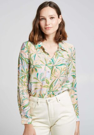 Chemise à manches longues à boutons avec un motif floral pastel, ornée d'accents verts, roses et bleus, fabriquée en tissu léger, associée à un pantalon blanc.