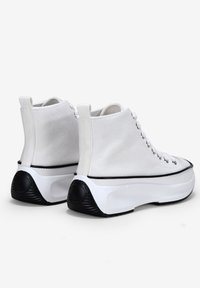 Sneaker alte in tela bianca con suola in gomma nera. Presentano asole e lacci; tallone testurizzato con accento rotondo.