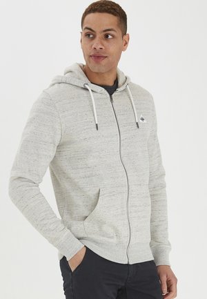 Haut de sweatshirt zippé gris clair en tissu texturé, avec une poche avant, des cordons de serrage et un petit logo sur la poitrine.