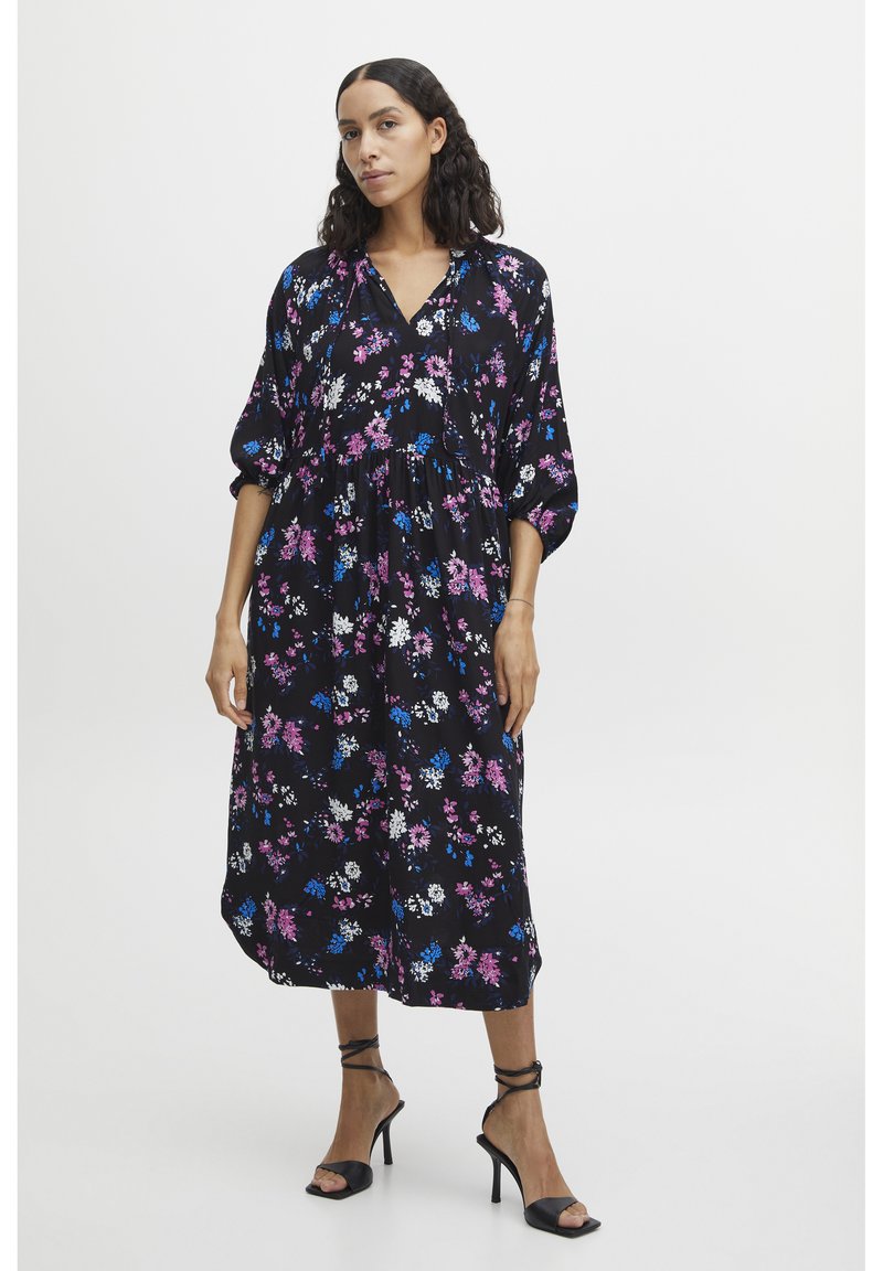 Robe midi florale en tissu noir avec des fleurs roses, bleues et blanches, présentant une coupe décontractée, un col en V et des manches bouffantes.