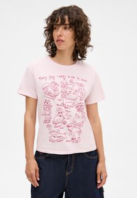Light pink T-shirt featuring playful, red line-drawn illustrations of animals wearing various hats and a humorous text caption.