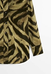 Button-up shirt in green and black zebra pattern, featuring a soft texture, long sleeves, and a single chest pocket.