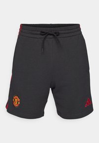 Pantaloni corti neri in misto cotone. Presentano una vita con cordoncino, strisce laterali rosse e logo ricamato del Manchester United sulla gamba sinistra.
