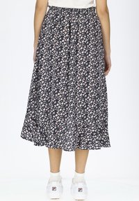 Floral Midi-Rock, dunkelblauer Hintergrund mit kleinen pinken und weißen Blumen, elastischer Bund, fließende Form, kombiniert mit weißen Sneakers.