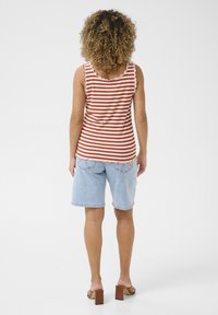 Canotta a righe ribattuta rossa e bianca con bordi scallop, abbinata a pantaloni shorts in denim blu chiaro e sandali con tacco cubano marroni.