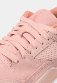 Pink sneakers med mesh- og ruskindsmaterialer. Har flade snørebånd, tekstureret overflade og et logo på tungen. Glat, afrundet form.