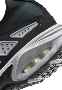 Czarny sneaker z teksturowaną tkaniną i szarymi akcentami, z widoczną jednostką amortyzacji powietrznej oraz wzorzystą gumową podeszwą zapewniającą przyczepność.