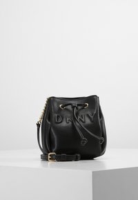 Černá kožená kabela ve tvaru kbelíku s vyraženým logem "DKNY", stahovací šňůrkou, zlatými kovovými prvky a odnímatelným ramenním popruhem.