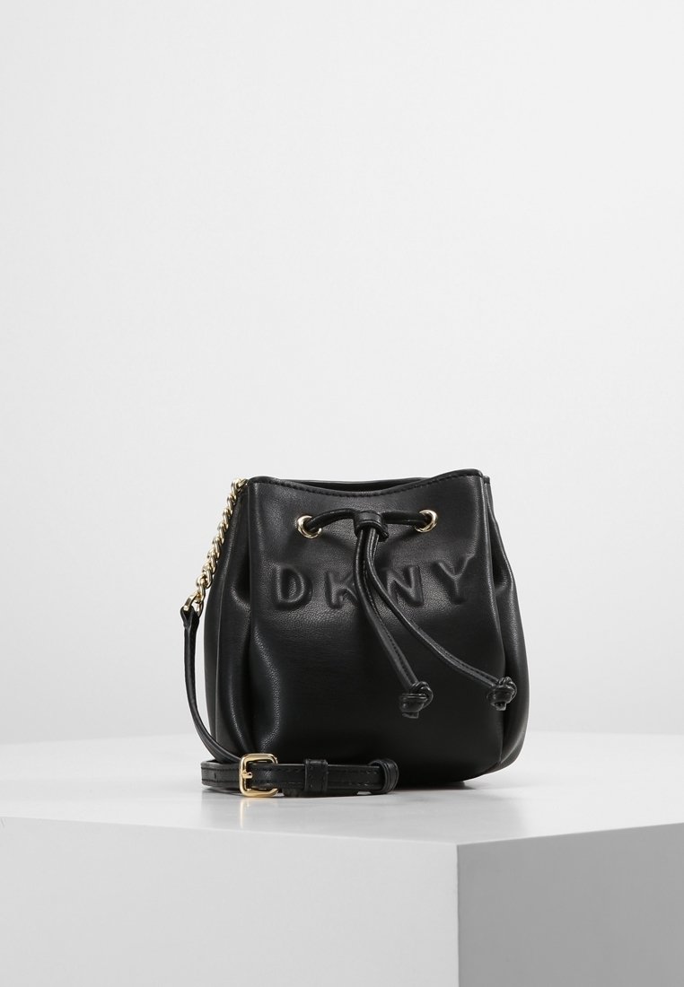 Černá kožená kabela ve tvaru kbelíku s vyraženým logem "DKNY", stahovací šňůrkou, zlatými kovovými prvky a odnímatelným ramenním popruhem.