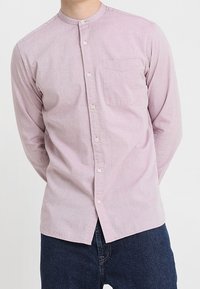 Hellrosa, langärmliges Hemd mit Knöpfen, Stehkragen und Brusttasche; verfügt über einen weichen, strukturierten Stoff und Knopfverschlüsse.