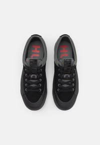 Zapatillas negras con una mezcla de ante y material de malla. Detalles en gris, cordones negros y logo en la plantilla en rojo. Punta redondeada con suela de goma.