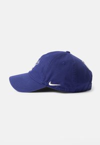 Ljubičasti pamučni bejzbol šešir sa zakrivljenim vizirima, s bijelim Nike logotipom i izvezenim detaljima na prednjoj strani.