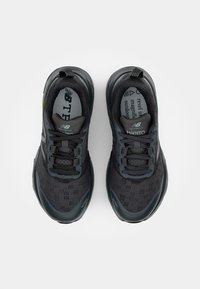 Baskets de sport noires avec une tige en mesh, des détails texturés et des accents bleu foncé. Présentent une semelle rembourrée et un système de laçage pour un maintien sécurisé.