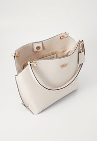 Borsa a mano in pelle crema con una texture liscia, dettagli in metallo dorato, chiusura zip e forma curva. Presenta un interno con una fodera stampata.