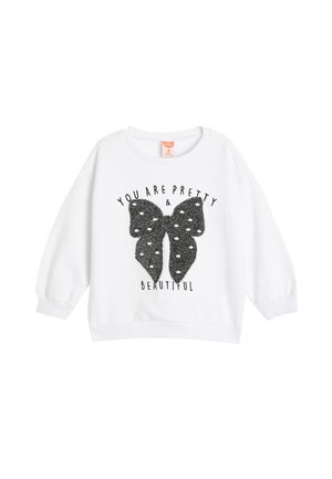 Sweatshirt blanc avec un col rond et des manches longues. Présente un graphique de papillon noir avec une surface texturée et scintillante, ainsi que du texte imprimé.