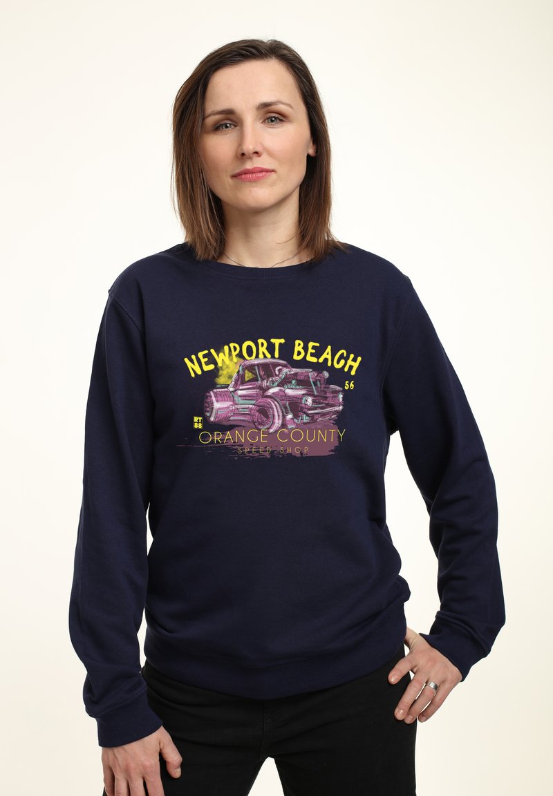 Felpa blu navy con grafica di una macchina vintage e testo "NEWPORT BEACH" in giallo. Tessuto morbido, maniche lunghe, polsini e orlo a costine.