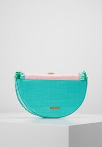 Borsa a mezzaluna turchese con finitura testurizzata e parte superiore rosa. Presenta una chiusura in metallo e decorazioni a frange.