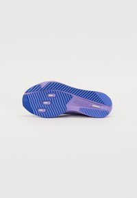 Suela de zapatilla de correr ligera en púrpura y azul. Presenta una superficie texturizada con ranuras para tracción y tres protuberancias circulares para amortiguación.