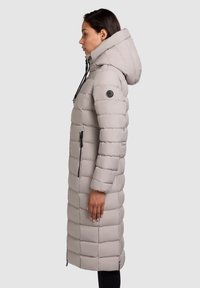 Garšs, gaiši pelēks pūku mētelis ar kapuci, ar izšūtu rakstu, sānu rāvējslēdzējiem un apaļu logotipa uzlīmi uz roku.