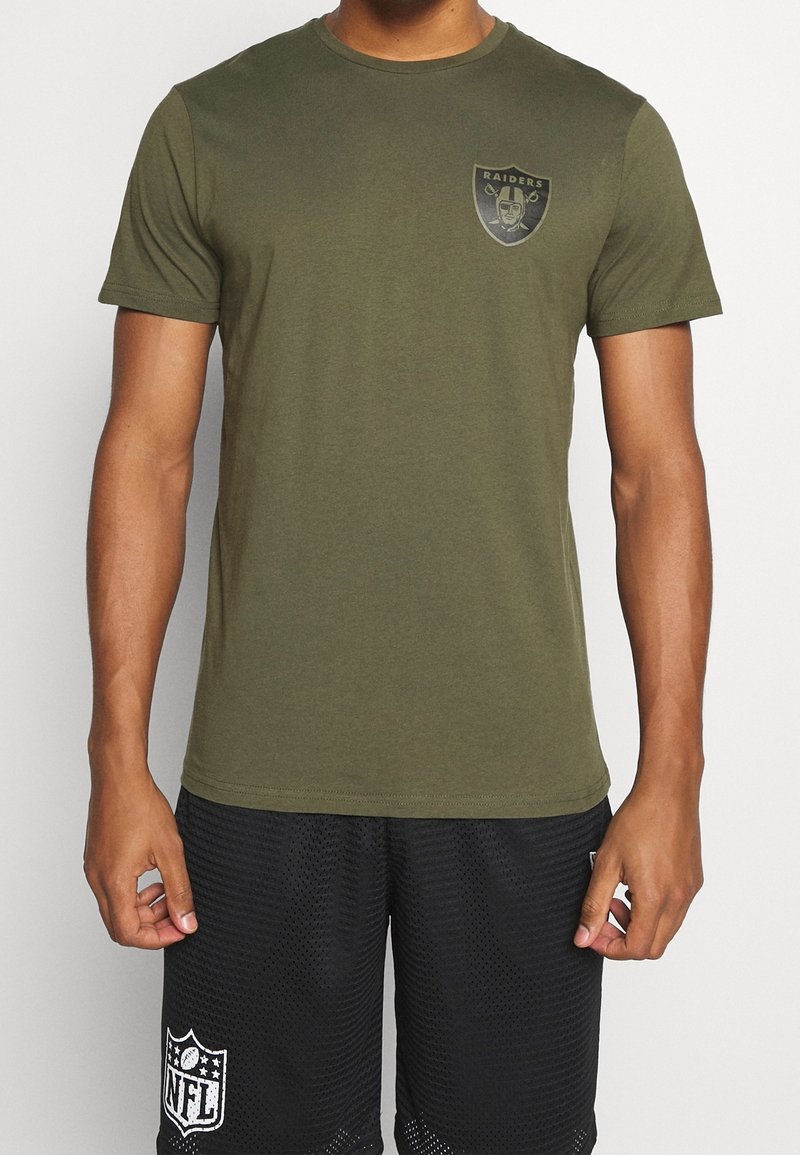 Olivgrön T-shirt med kort ärm av bomull, med en svart Raiders-logotyp på bröstet. Slät textur och rundad halsringning.