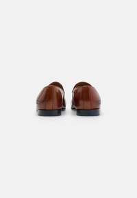 Brune skinnsko med glatt finish, slip-on design og lav hæl. Har subtile sømdetaljer og rund tå.