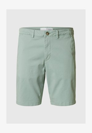 Kerged rohelised lühikesed püksid puuvillast, millel on üks eesmine nööbilukustus, vöökohad ja puhas, lihtne disain ilma nähtavate mustriteta.