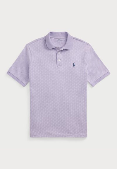 Lilla polo särk, millel on tekstuuriga muster, lühikesed varrukad, krae ja kolme nupuga kinnitus. Rinnal on väike tumesinine logo.