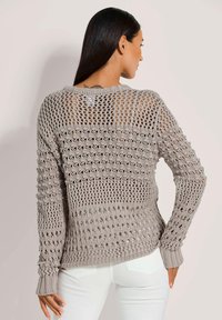 Grau gestrickter Pullover mit offenem Häkelmuster, rundem Halsausschnitt und langen Ärmeln. Strukturiertes Material mit gerippten Bündchen.