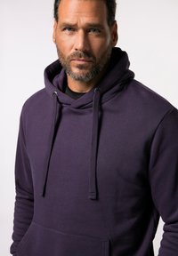 Fioletowa bluza z kapturem i sznurkiem, z prążkowanymi mankietami oraz przednią kieszenią. Materiał wydaje się miękki i teksturowany, odpowiedni do codziennego noszenia.