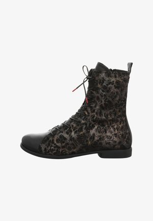 Lace-up ankle boot in black leather and textured dark fabric, featuring a distinctive pattern and red accent on laces, flat sole.