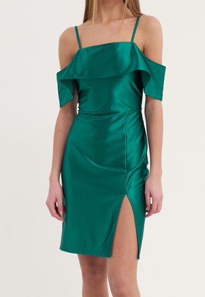 Grøn satin kjole med off-shoulder flæseærmer, tætsiddende silhuet og højt slid på den ene side. Glat tekstur og blank finish.
