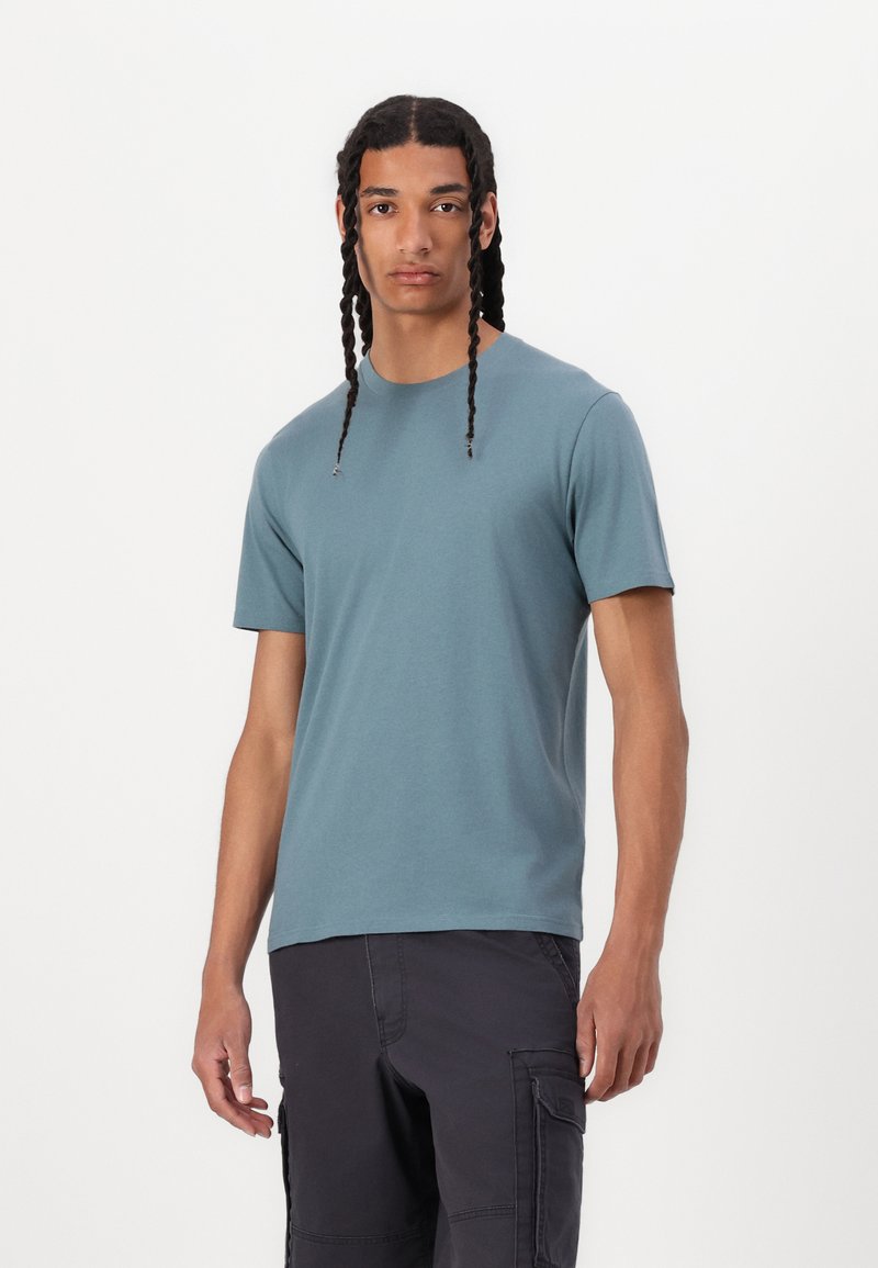 T-shirt de manga curta para homem em verde-água, feito de algodão macio. Apresenta um decote redondo e um ajuste relaxado, com uma textura suave e uniforme.