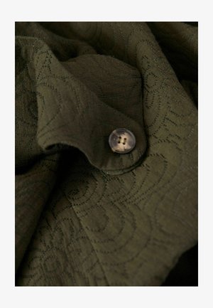 Olijfgroen stof met een gestructureerd draaiend patroon, voorzien van een doorzichtige plastic knop met vier gaten. Zachte en vloeiende uitstraling.