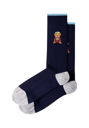 Navy blue crew socks with light gray toes and heels, light blue cuff, and a small embroidered figure wearing red and orange near the top.