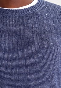 Maglione a maglia blu navy con un motivo testurizzato, colletto a coste e sottili tocchi di colore più chiaro sparsi nel tessuto.