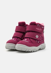 Stivali fucsia con fodera in pelliccia sintetica rosa, dotati di due cinturini in Velcro e motivi a fiocco di neve sui lati. La suola in gomma garantisce aderenza.