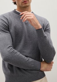 Grau gestrickter Rundhalspullover aus feinem Material. Mit gerippten Bündchen und Saum, glatter Textur und figurnaher Passform.